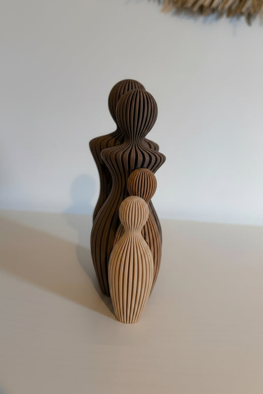 Brown ceramic sculpture of a woman on a white surface with a textured wall in the background